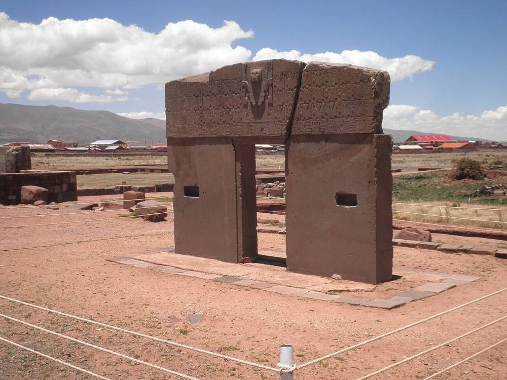 A monolithic stone gateway at the Tiwanaku ruins in Bolivia under a blue sky.