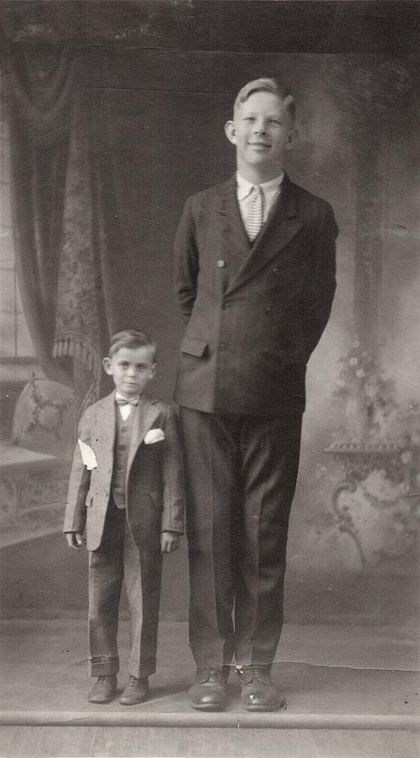Photograph of a very tall boy standing beside a boy of ordinary height.