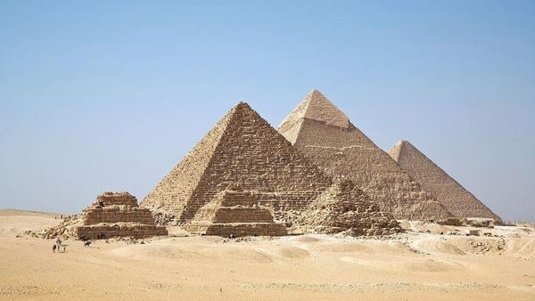 Aerial view of the three main pyramids of Giza, with the smaller queens' pyramids in front, on the desert plateau.